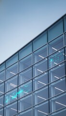 Obraz premium Modern glass office building facade with digital data visualization overlays under a clear sky