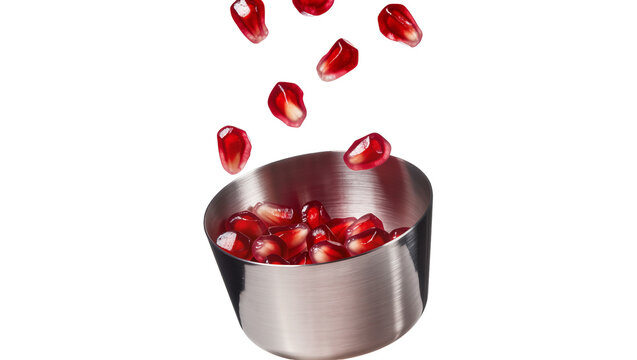 Shiny metal bowl filled with fresh pomegranate seeds, some falling isolated on transparent background