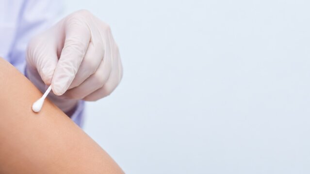 Medical worker swabbing arm during clinical procedure