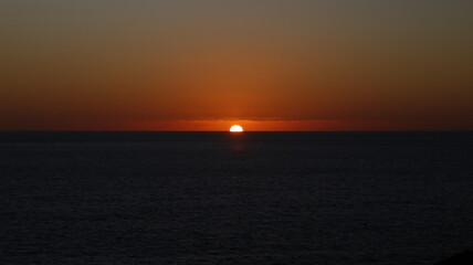 Fototapeta premium Sun dips low, painting sky in warm orange hues