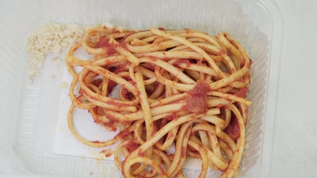 Bucatini pasta with tomato sauce in container