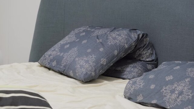 Bed with patterned blue pillows and headboard