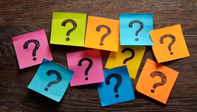 assorted colorful sticky notes with question marks scattered on a wooden surface