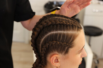 Naklejka premium Hair braiding. Hairdresser working with teenage girl in salon, closeup