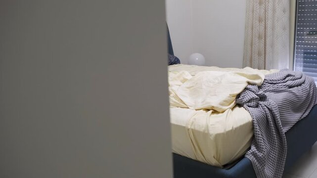 Unmade bed with rumpled sheets and blankets in bedroom
