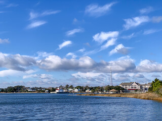 Fototapeta premium View of the Manteo waterfront along Roanoke Sound with coastal marsh, calm waters, and dramatic clouds on North Carolina's Outer Banks.