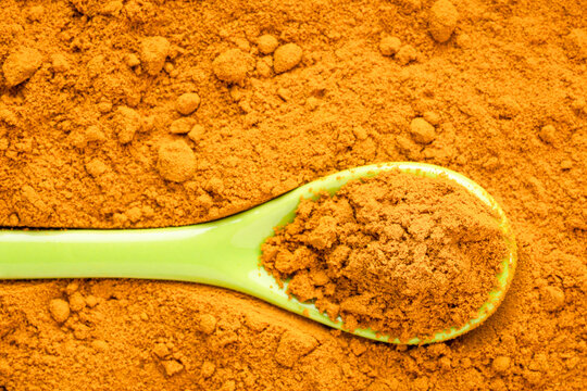 Turmeric root powder background and texture with a spoon