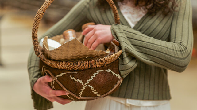 Woman holding a woven basket filled with items and wrapped in paper