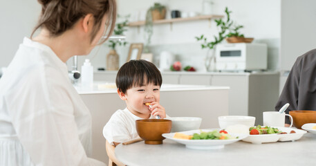 A boy eating a meal with his parents and family. © buritora