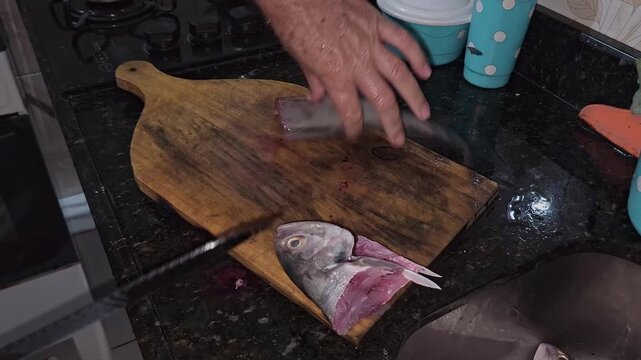 Detailed shot of hands cleaning a fresh catch with a sharp knife in a kitchen