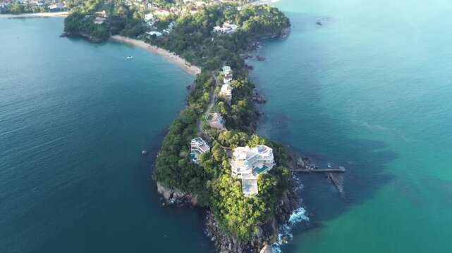 A paradisiacal cape with clear tropical waters and a city nestled among mountains in the background. Praia da Santa Rita and Praia da Enseada (Ubatuba), Brazil
