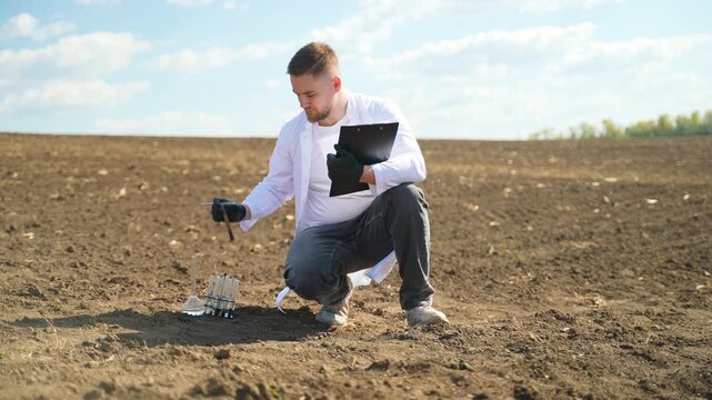 Agronomist scientist checking soil quality on a farm field