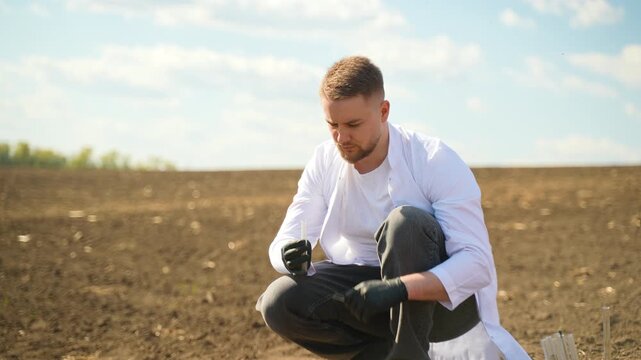 Agronomist scientist analyzing soil sample in field