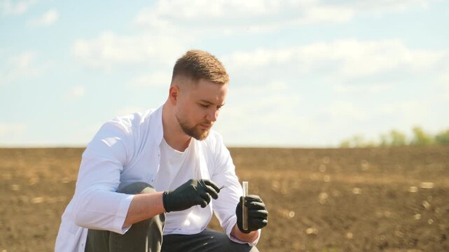 Male agronomist testing soil quality in a field