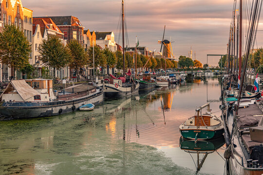 A quiet scene in Delfshaven with boats floating on the calm slough at sunset.