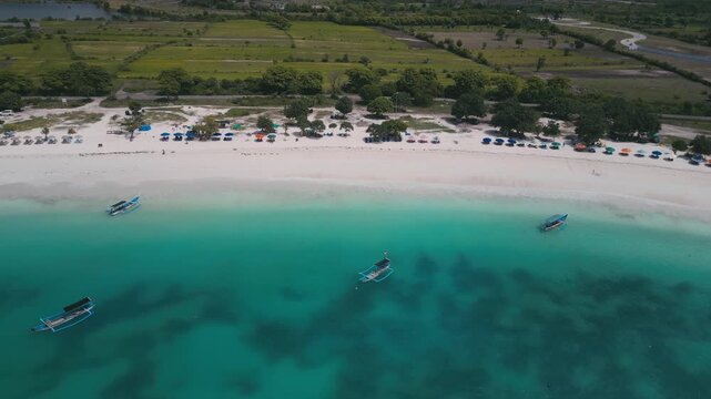 Aerial Cove Beach With Rocky Rockpool And Colorful Umbrellas On Curved Sand,Families Swimming Near Reef Patches,Lively Summer Energy And Clear Shallow Water,Tanjung Aan,Kuta,Lombok,Indonesia