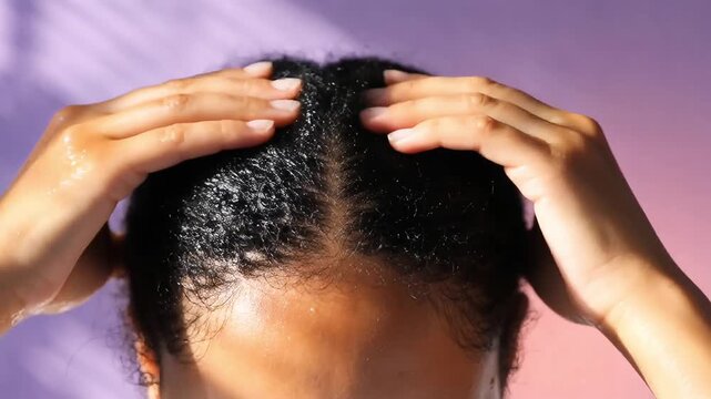 Close-up of woman fingers massaging wet black hair parting