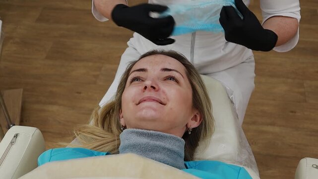A female doctor, a professional cosmetologist, prepares a patient's face for a procedure