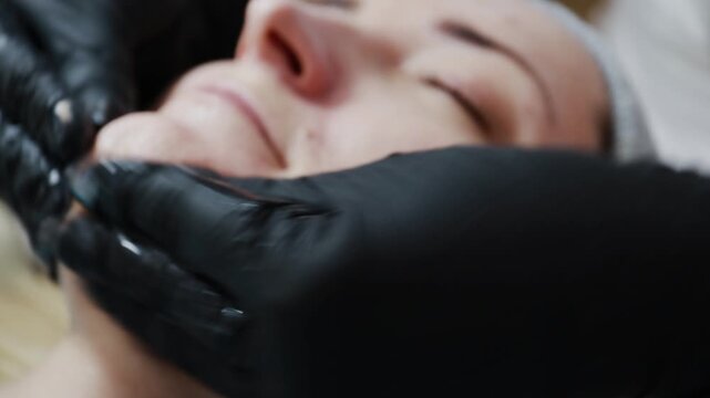 A female doctor, a professional cosmetologist, prepares a patient's face for a procedure