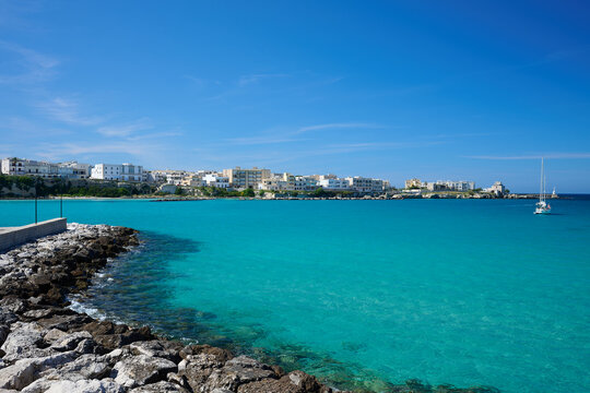 View over seawall \ groyne \ harbour wall \ harbor wall with one yacht on turquoise sea under blue sky