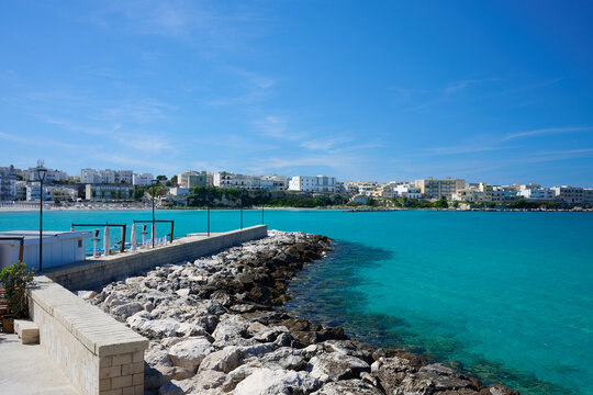 View over seawall \ groyne \ harbour wall \ harbor wall with no boats on turquoise sea under blue sky
