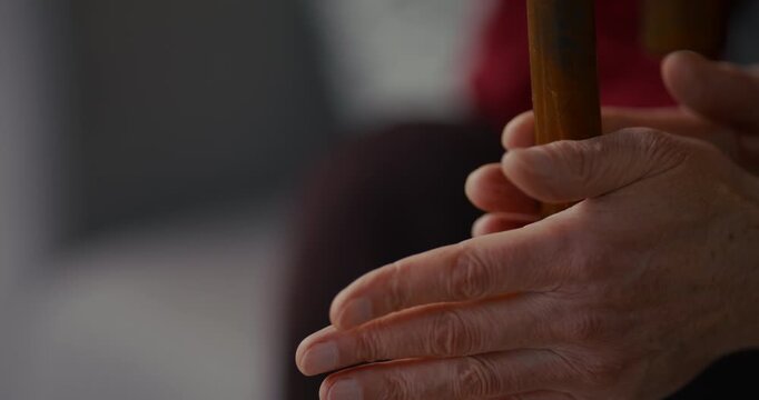 Close up of adult hands gripping a wooden pole indoors