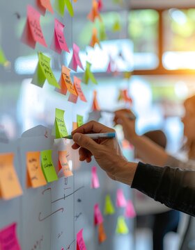 Professional writing on colorful sticky notes on office whiteboard during brainstorming session.
