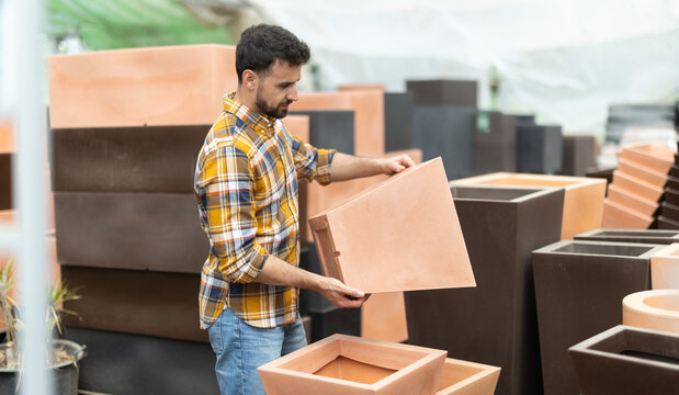 Among large number of goods, man chooses large flower pot-tub. Equipment and devices for gardening and floriculture