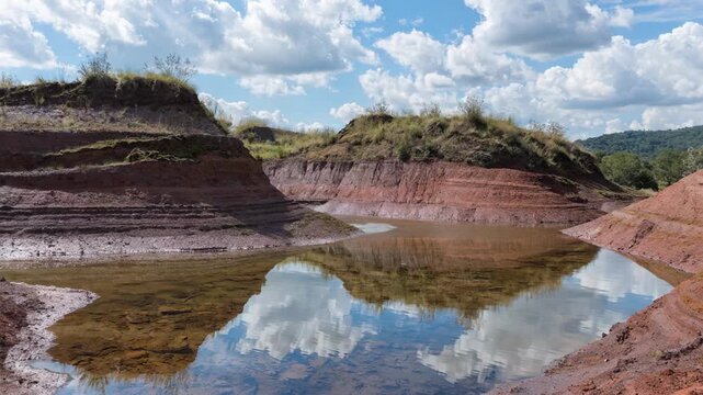 Medium shot capturing partly reclaimed red mud tailings area with emerging vegetation on berms and residue ponds emphasizing environmental recovery efforts