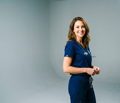 Smiling Brunette Female Medical Professional in Navy Blue Scrubs Standing in Studio
