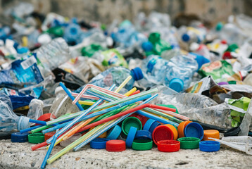 Fototapeta premium Pile of colorful single use plastic straws and bottle caps in garbage dump