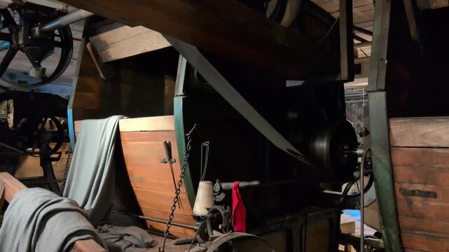 Video of a massive wooden washing machine driven by belts, pulleys, and a steel wheel powered by river energy, demonstrating early industrial textile cleaning technology preserved
