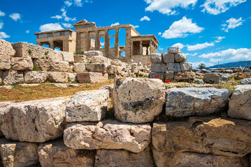 Fallen stones on the Acropolis of Athens with The Erechtheion in background, cultural and architectural landmarks of ancient Greece. © Kyaw Thiha