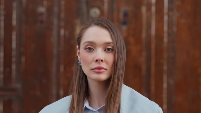 Model takes various poses in front of wooden wall. She smiles and shows different expressions while enjoying the warm daylight in an outdoor setting.