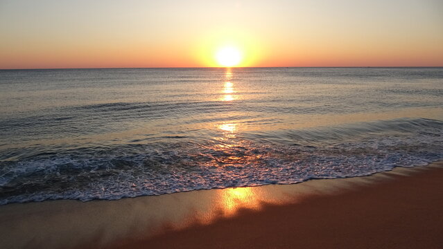Majestic golden sunrise over the sea with sun reflection on waves.
Golden morning light reflects beautifully on the sea surface and wet sand beach as gentle waves wash ashore in Gangneung.