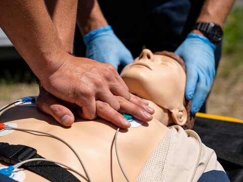 Medical professionals practicing chest compressions on a CPR training mannequin during a drill.