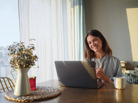 Cheerful Woman Working on Laptop in a Bright Modern Room