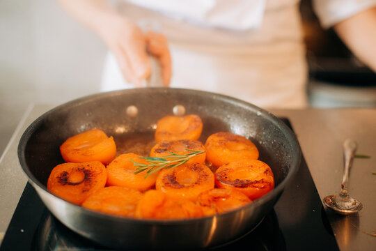 Caramelized apricots with rosemary in frying pan close-up