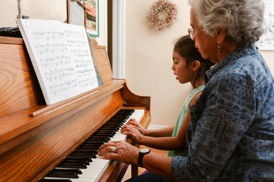 Grandmother Teaches Granddaughter Piano at Home in Afternoon