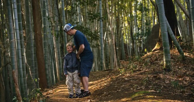 Father and son doing multiple poses on dirt path surrounded by bamboo grove in Japan