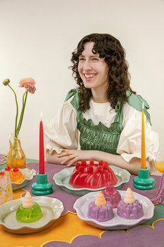 Smiling woman sitting at a colorful festive table with jelly desserts