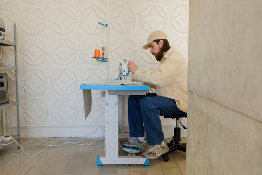 The guy sews clothes in the creative space.