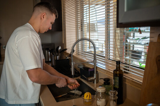 Young man washing dish in kitchen sink
