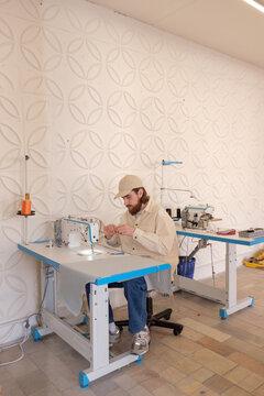The guy sews clothes in the creative space.