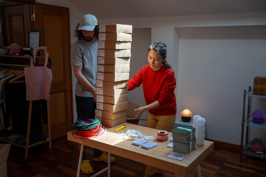 Team stacks tall pile of parcels in workspace