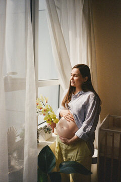 Pregnant woman by the window in the morning light.