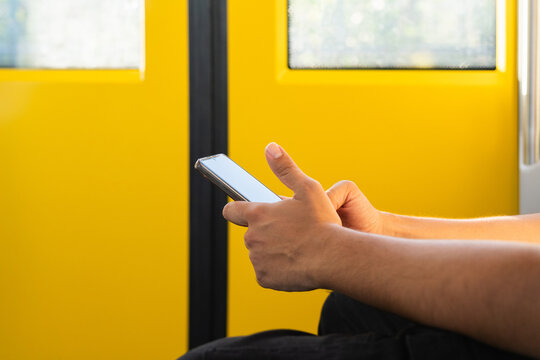 Passenger using smartphone on public transport with yellow background