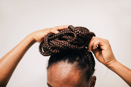 Crop of anonymous african faceless woman with acne, braiding her hair