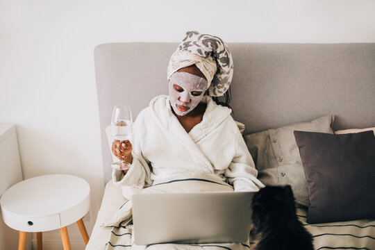 African american woman with beauty mask working from home on laptop 