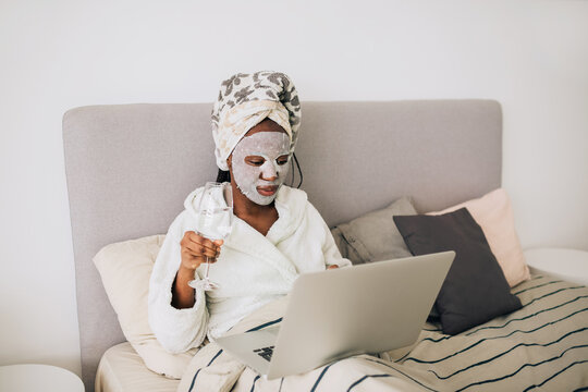 African american woman with face mask working on laptop from home  
